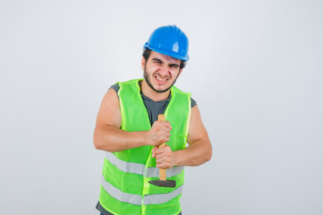 时尚年轻的建筑工人穿着工作服拿着锤子 看上去更强壮正视图正面建筑商相机