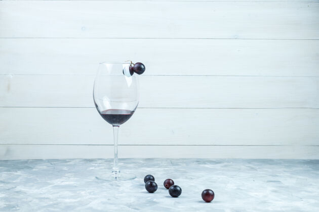 壁板一杯葡萄酒和黑葡萄 背景为灰色和木质 侧面视图大集饮食