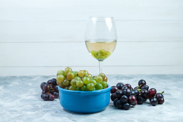 葡萄侧视图葡萄在碗里与一杯葡萄酒在肮脏的灰色和木制背景水平葡萄有机成熟