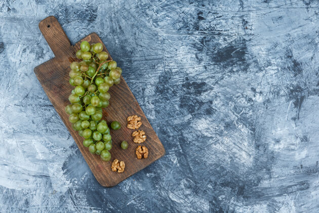 葡萄平放在深蓝色大理石背景的砧板上的白葡萄 胡桃木水平的自由空间为您的文字自然秋天饮食