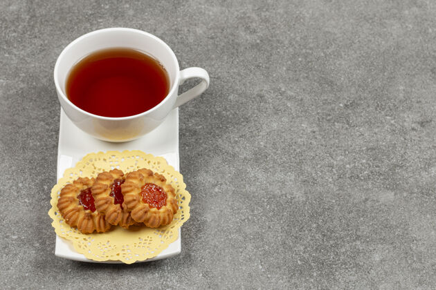 饼干在茶碟上放一杯茶和果冻饼干美味茶果冻