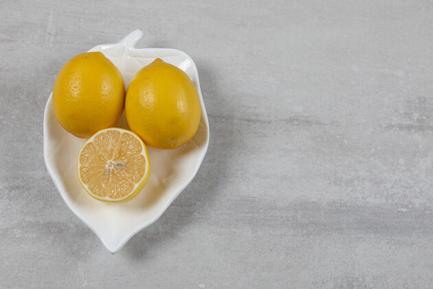 新鲜在大理石表面的盘子里放两个半柠檬可口盘子蔬菜