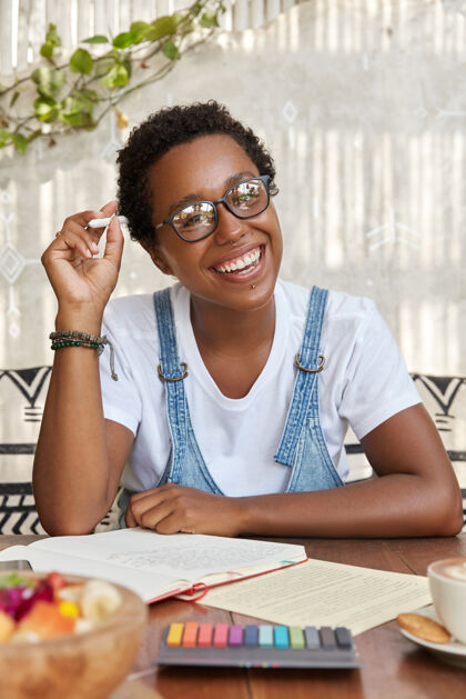 作者开朗的黑人妇女的照片 带着灿烂的笑容 思考着解决问题的办法笔记本设备室内