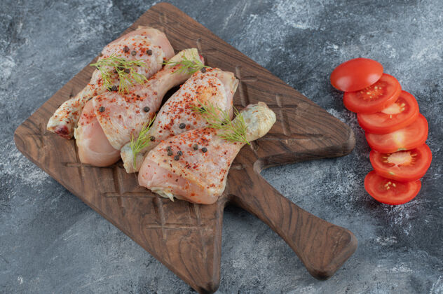 菜肴把生鸡腿和有机西红柿片放在菜板上蔬菜香草晚餐