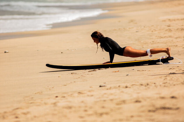 起床美丽的女孩站在沙滩上的冲浪板上乐趣划桨休闲