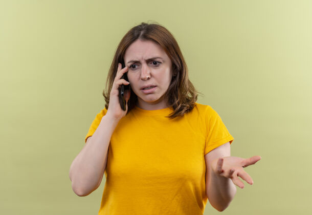 电话一个不快乐的年轻随意的女人在电话里说话 在隔离的绿墙上空手而归空虚手随意