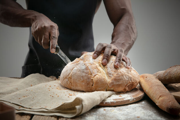 休闲非洲裔美国人用菜刀切新鲜面包的特写镜头谷类男性厨房