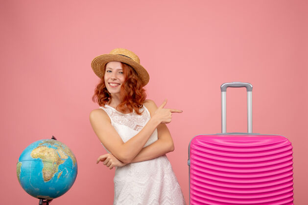夏天年轻女性游客的正面图 粉红色的墙上挂着粉红色的包人航行包