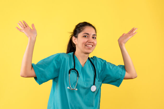 听诊器年轻女医生在黄墙上张开双手的正面图药手年轻女医生