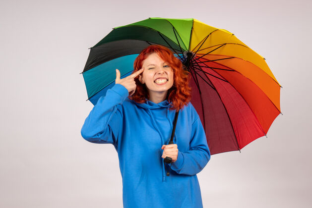 阳伞白色墙壁上带着彩色雨伞的年轻女性的正视图人情绪天气