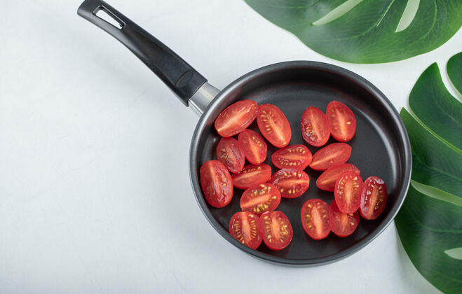 健康煎锅上樱桃番茄的俯视图桌面扁平一半