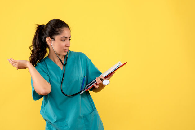 站着身穿制服的女医生拿着文件站在黄色的墙上护士地方纸