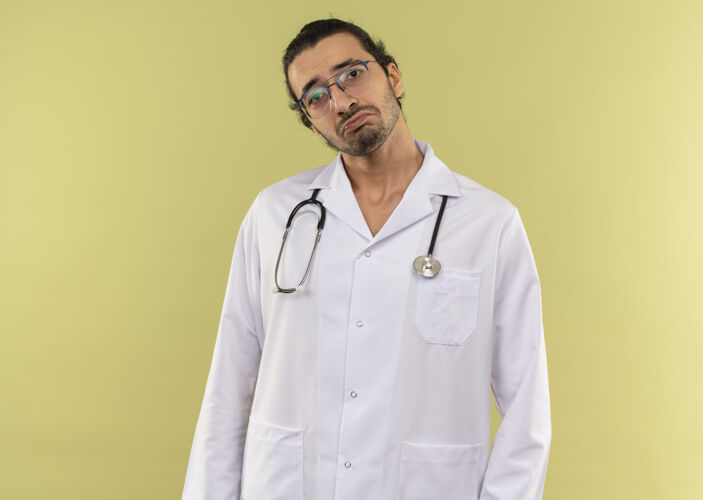 医生悲伤的年轻男医生戴着眼镜 穿着白色长袍 听诊器放在隔离的绿墙上 留着复印空间男性穿年轻