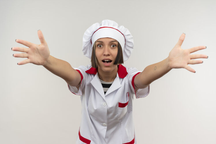 厨师印象深刻的年轻女厨师在厨师制服伸出双手孤立在白色伸展烹饪年轻