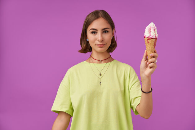 年轻十几岁的女孩 快乐快乐 深色短发 拿着冰淇淋穿着绿色t恤 手镯 戒指和项链圆锥体T恤深色