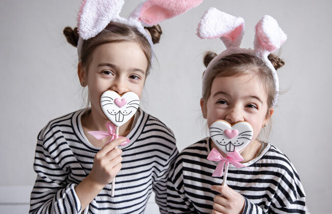乐趣两个有趣的小妹妹正以兔子脸的形式与复活节姜饼合影兔子女孩耳朵
