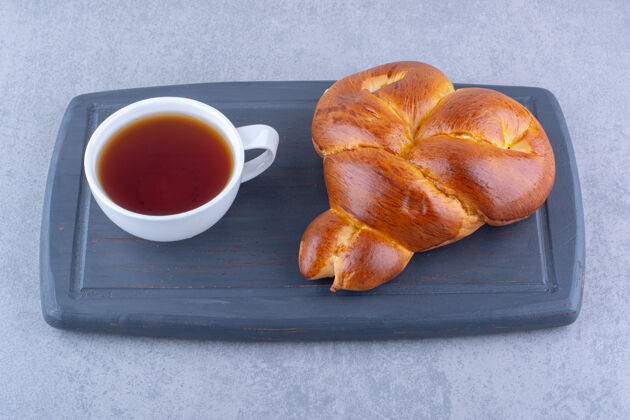 美味早餐供应茶和甜面包在大理石表面的木板上糕点烘焙食品杯