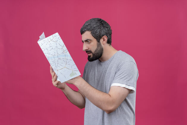 粉色迷茫的年轻英俊的白种人旅行家男子拿着地图看着孤立的粉色空间男人旅行者空间