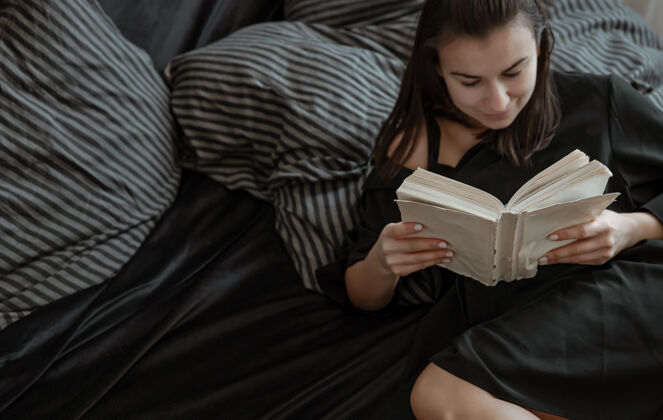 休息一个美女躺在舒适的床上看书的特写镜头毯子文学特写