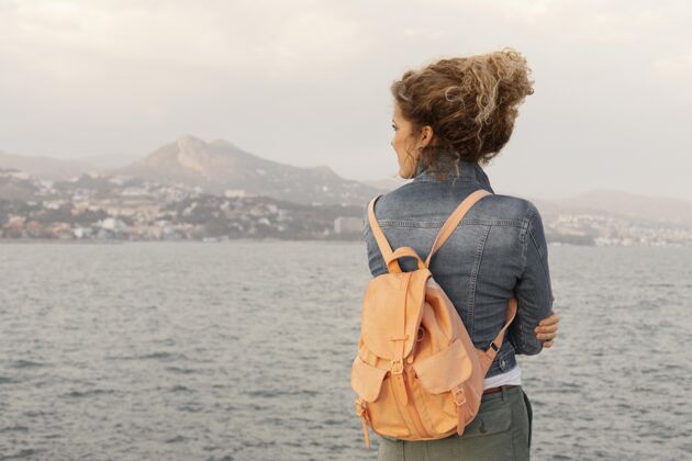 世界中等身材的女人背着背包在海边水平旅行度假
