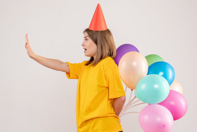 情感年轻的女性把彩色的气球藏在白色的背上人生日气球