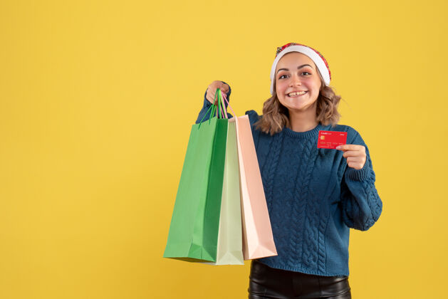 黄色年轻女子持银行卡和包裹购物后上黄色购物年轻的女性视图