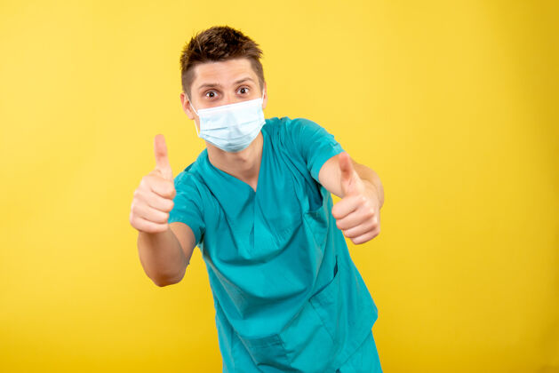 医院正面图：年轻的男医生穿着医疗服 黄色背景上带着无菌口罩人背景男性