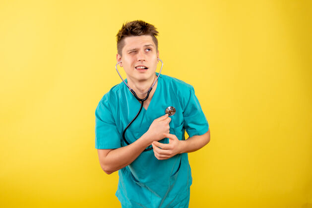 医院前视图年轻男医生穿着医疗服 黄色背景上带听诊器人医学健康
