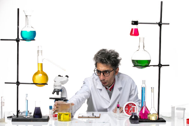 科学正面图身穿白色医疗服的中年科学家正坐在桌子前拿着解决方案实验室外套坐着医学