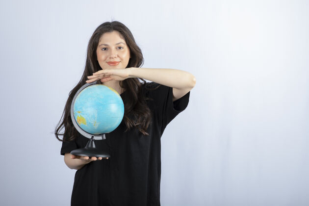 站立黑发女人拿着地球仪摆姿势休闲青少年情感