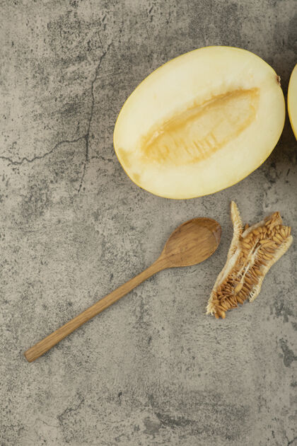 新鲜把美味的黄瓜切成两半放在大理石表面 放在木勺旁边热带种子切的