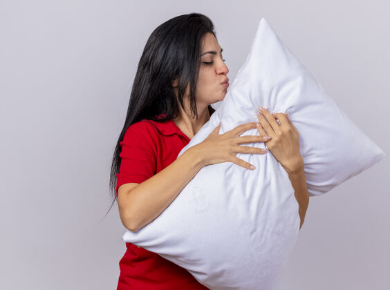 拥抱年轻的白种人病女孩抱着枕头做亲吻动作 闭上眼睛 在白色背景上与复制空间隔离关闭手势枕头