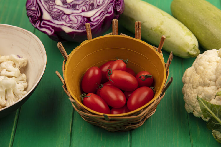 农业一桶新鲜的红梅西红柿的顶视图 紫色的卷心菜菜花和芹菜被隔离在绿色的木墙上桶蔬菜观点