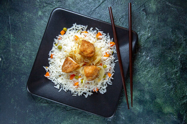 正餐在黑暗的桌子上 盘子里放着美味的煮米饭 里面有豆子和肉风景炸鸡肉