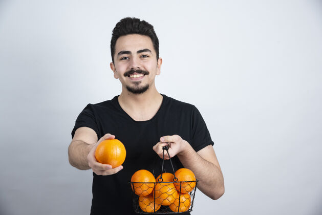 水果黑发男模特站着摆着橙色水果的姿势时尚食物休闲