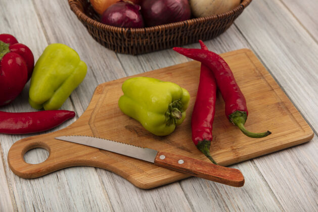 木材顶视图的贝尔和辣椒在一个木制的厨房板与刀子洋葱桶上的灰色木墙厨房菜肴食物