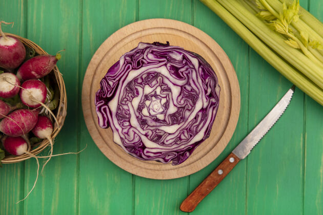 木材顶视图紫色卷心菜放在木制的菜板上 小刀插着萝卜放在桶上 芹菜被隔离在绿色的木墙上板食物有机