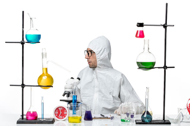 实验室正面图穿着特殊防护服的男科学家围坐在办公桌旁 拿着解决方案病毒罐子科学