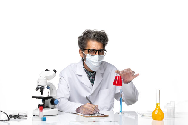 实验正面图穿着特殊套装的中年科学家坐着拿着装有红色溶液的烧瓶实验室专业科学