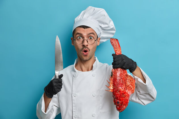 食物震惊的厨师大吃一惊 拿着锋利的刀 整条鲜鱼 快速准备健康食品 鲈鱼汤白种人工具餐馆