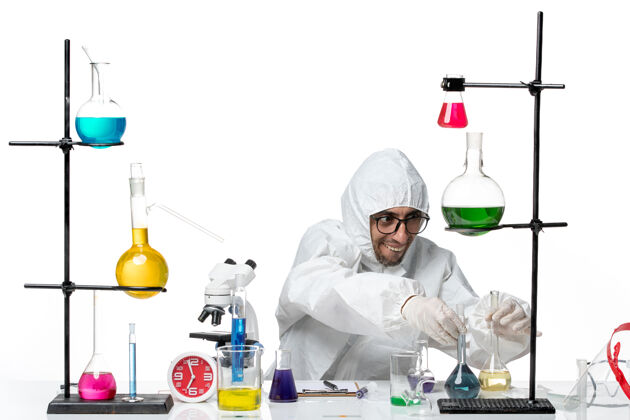 烧杯正面图穿着特殊防护服的男科学家拿着装有溶液的烧瓶实验室前面研究