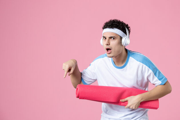 成人正面图穿着运动服的年轻男性 粉色墙上有瑜伽垫垫子人锻炼