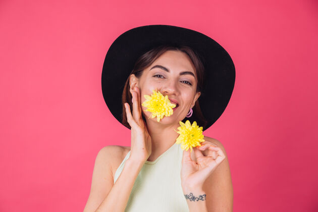 祝贺时尚的女人戴着帽子 微笑着两个黄色的紫苑 可爱的捧着一朵花在口中春意盎然 快乐的情感与世隔绝的空间长无忧无虑植物学