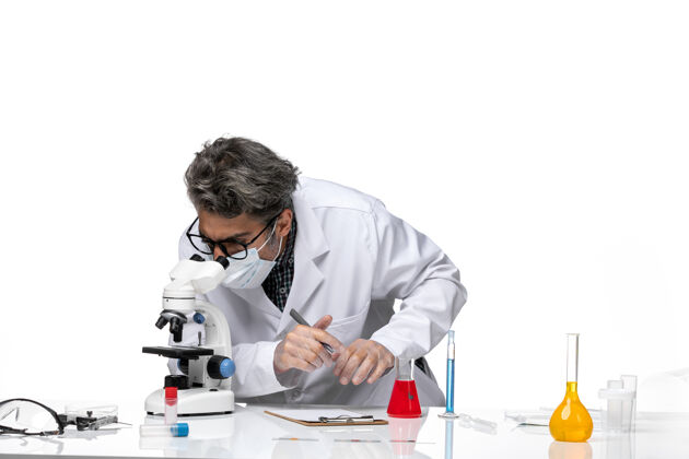 使用前视图中年科学家穿着特殊的白色西装使用显微镜人外套化学