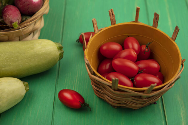 木材顶视图新鲜的红梅西红柿放在一个桶里 萝卜放在一个桶里 西葫芦被隔离在绿色的木墙上顶部西葫芦李子