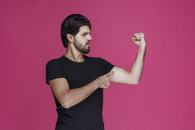 休闲穿黑衬衫的男人展示他的拳头和手臂肌肉模特成年人人类