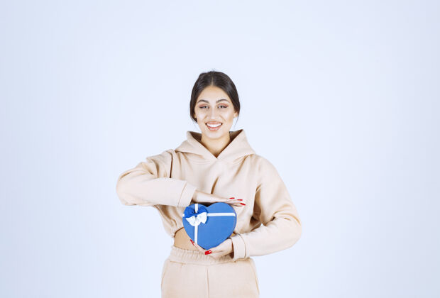姿势年轻女子拿着一个蓝色心形礼盒 看起来很开心工人周年纪念成人