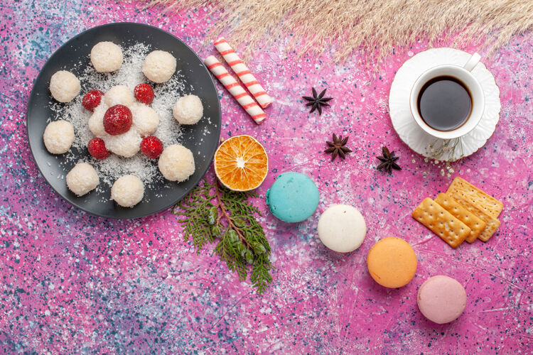 茶俯瞰美味的法国马卡龙与椰子糖和茶杯粉红色的表面顶视图麦卡龙饼干