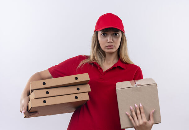 穿着一个穿着红色制服 戴着帽子 拿着盒子和披萨盒子的年轻送货女孩被隔离在白色的墙上送货年轻人盒子