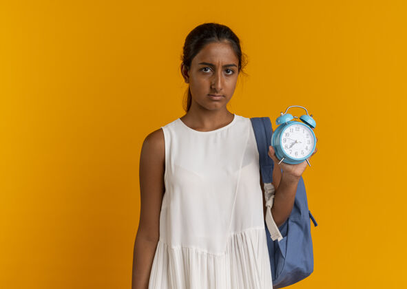女学生伤心的小女生背着书包拿着桔黄色的闹钟抱着闹钟年轻